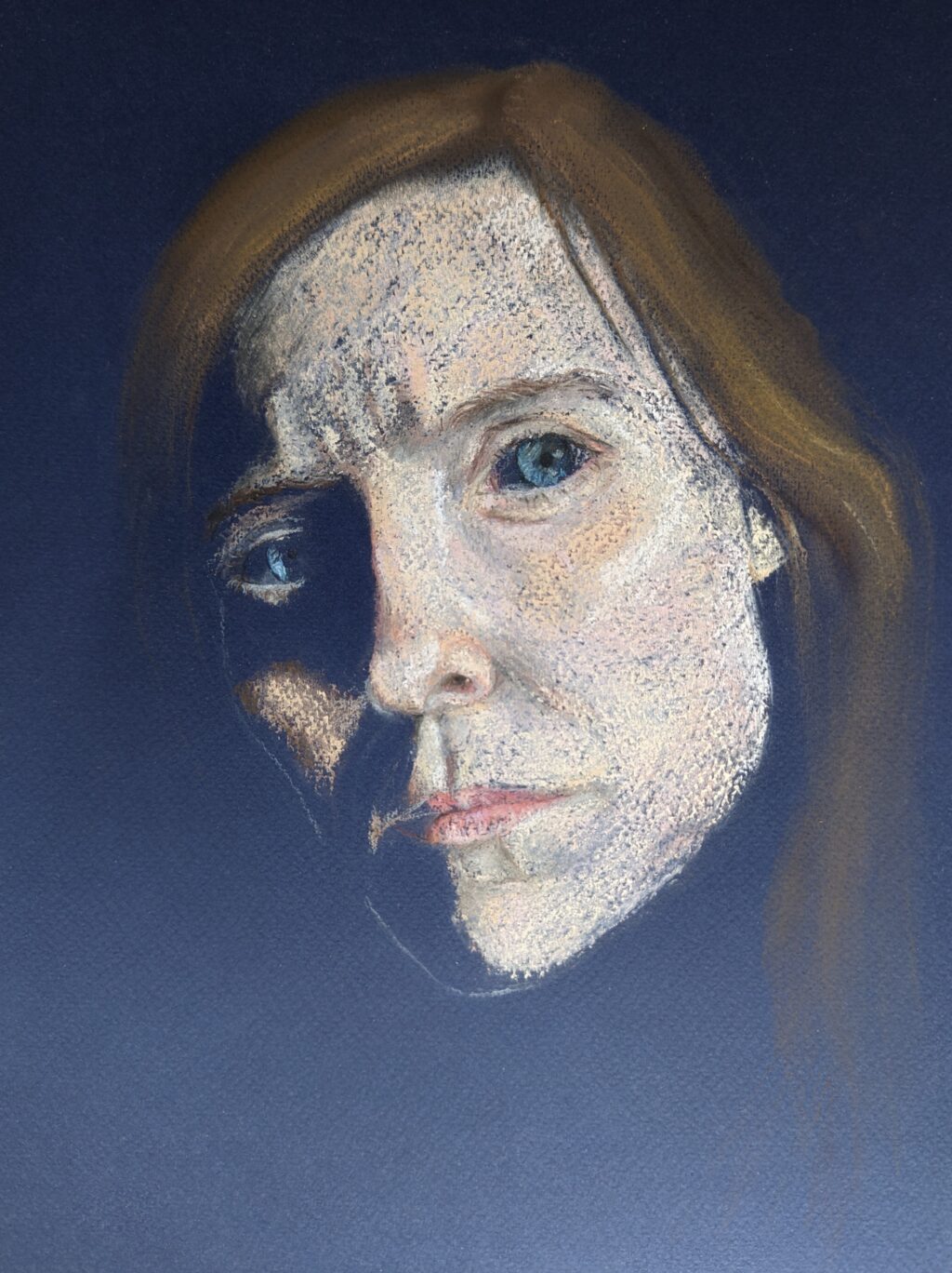 Drawn portrait of a woman’s face and hair coming out from a black background, the left of the face is in shadow and the woman looks at the viewer with piercing blue eyes.